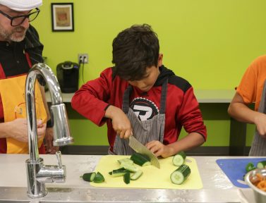 Un garçon coupe des légumes