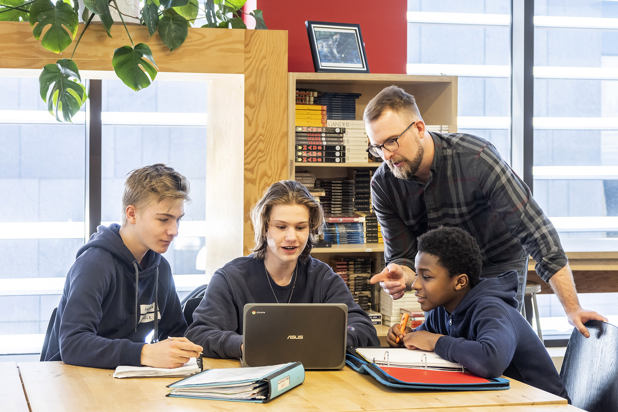Un professeur aide trois étudiants sur un ordinateur portable