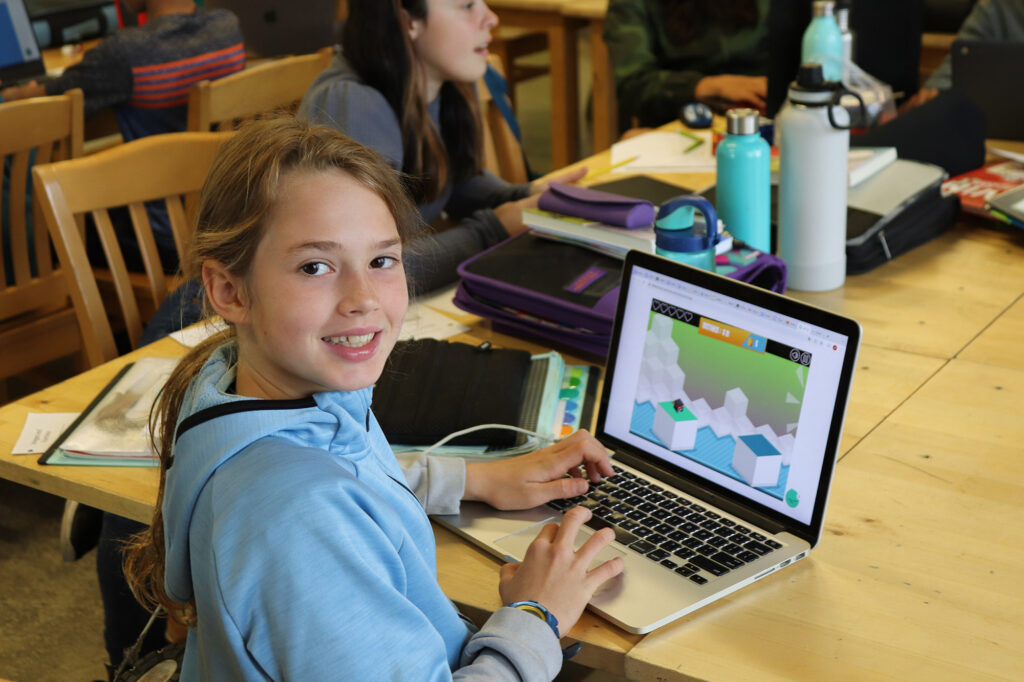 Étudiant sur un ordinateur portable regardant par-dessus son épaule et souriant